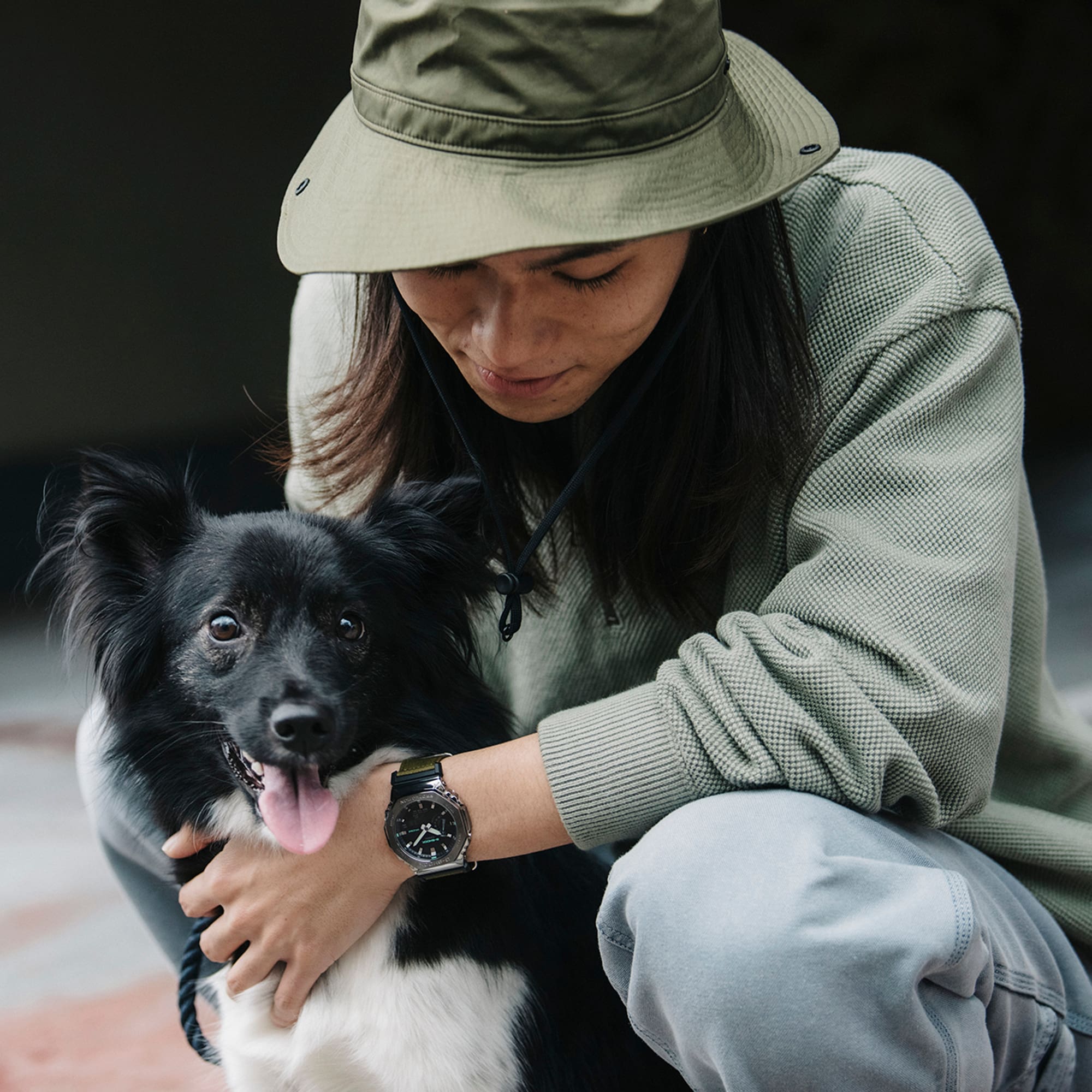 Man wearing a G-SHOCK GM2100CB-3A Metal covered analog digital utility watch with cloth band while petting a dog