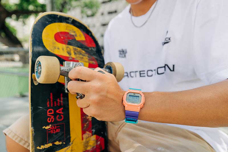 Skateboarder holding a skateboard wearing the G-SHOCK X In4mation DW5600IN4M234 digital watch