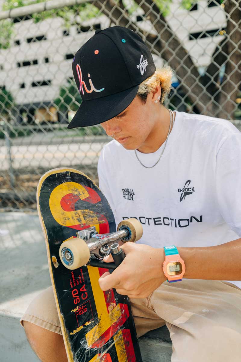 Skateboarder inspecting a skateboard wearing the G-SHOCK X In4mation DW5600IN4M234 digital watch