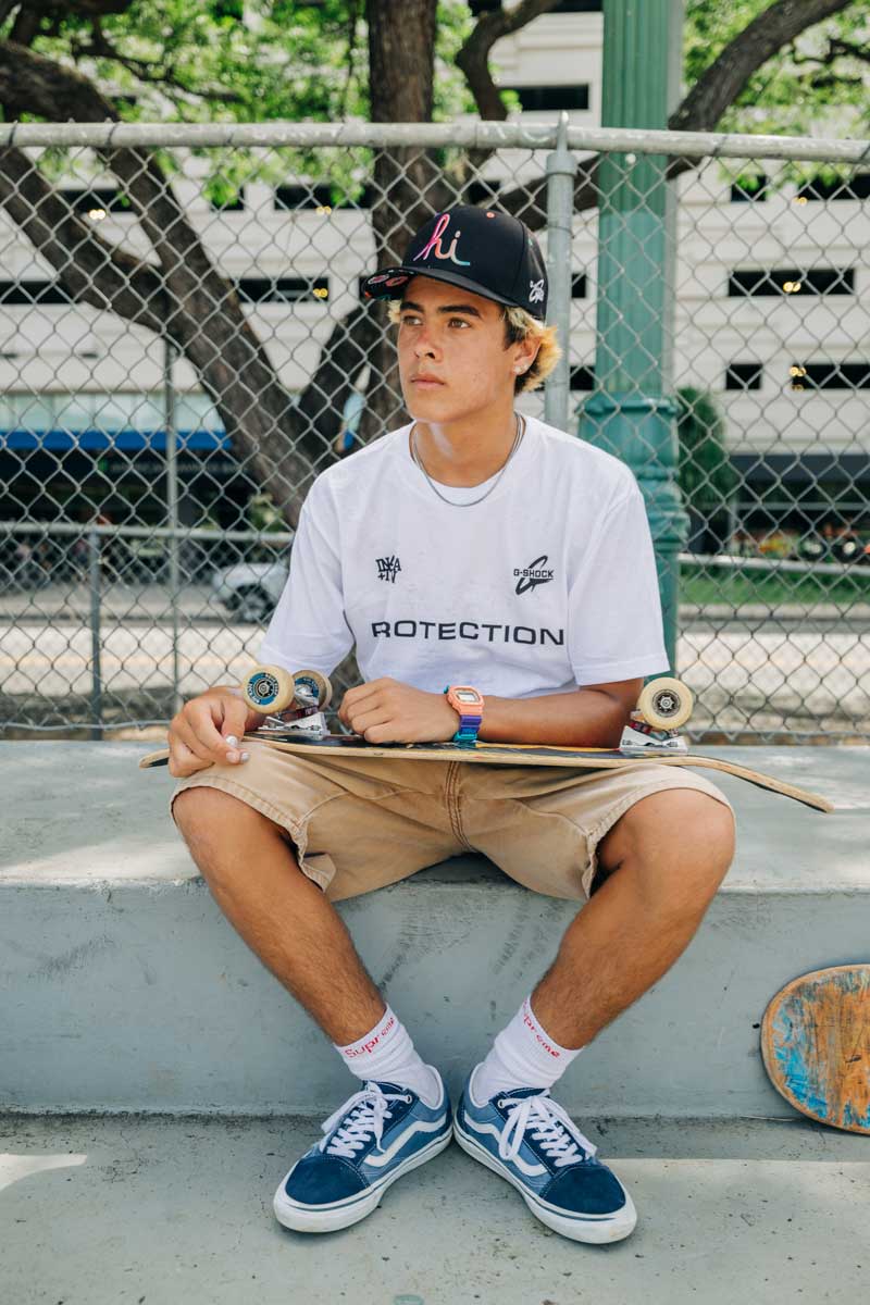Skateboarder sitting while holding a skateboard and wearing the G-SHOCK X In4mation DW5600IN4M234 digital watch