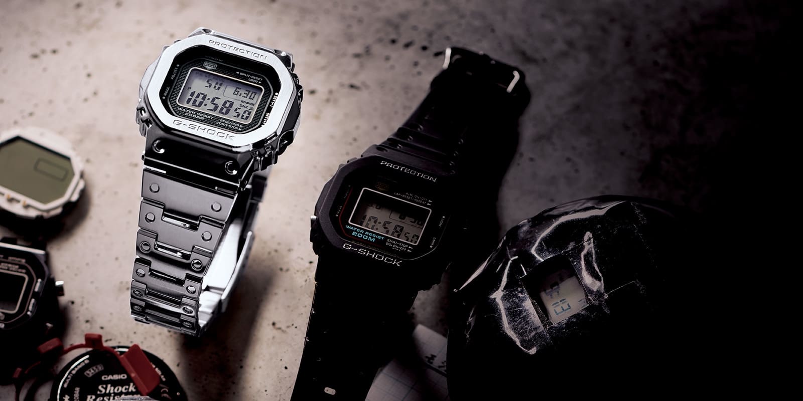 GMWB5000 and DW5000 series watches on a work table with various parts