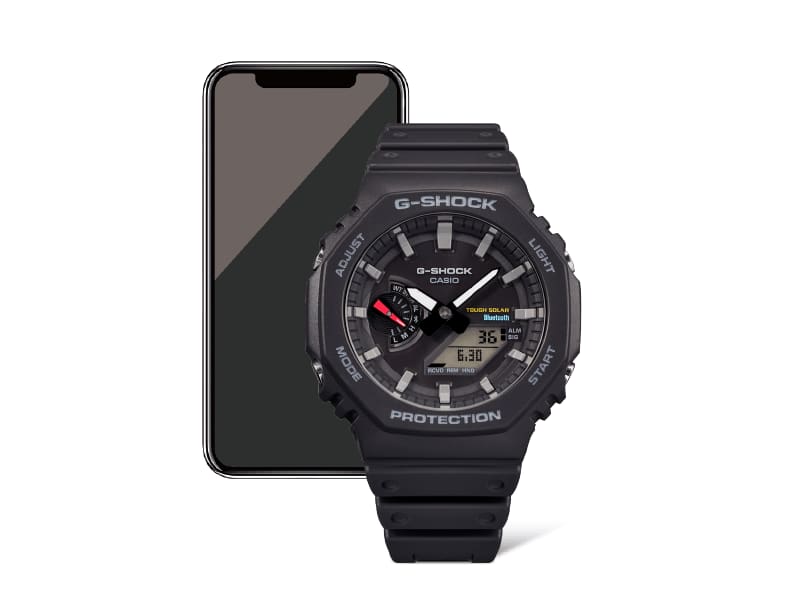 Black GAB2100 analog digital watch with mobile phone behind connoting bluetooth connectivity