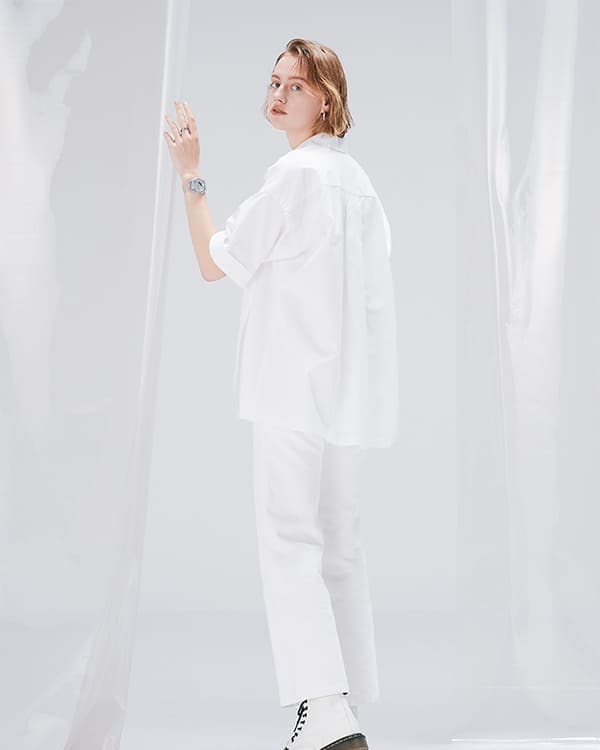 Model in white clothes looking over her shoulder touching clear fabric, while wearing transparent GMAS2100SK 