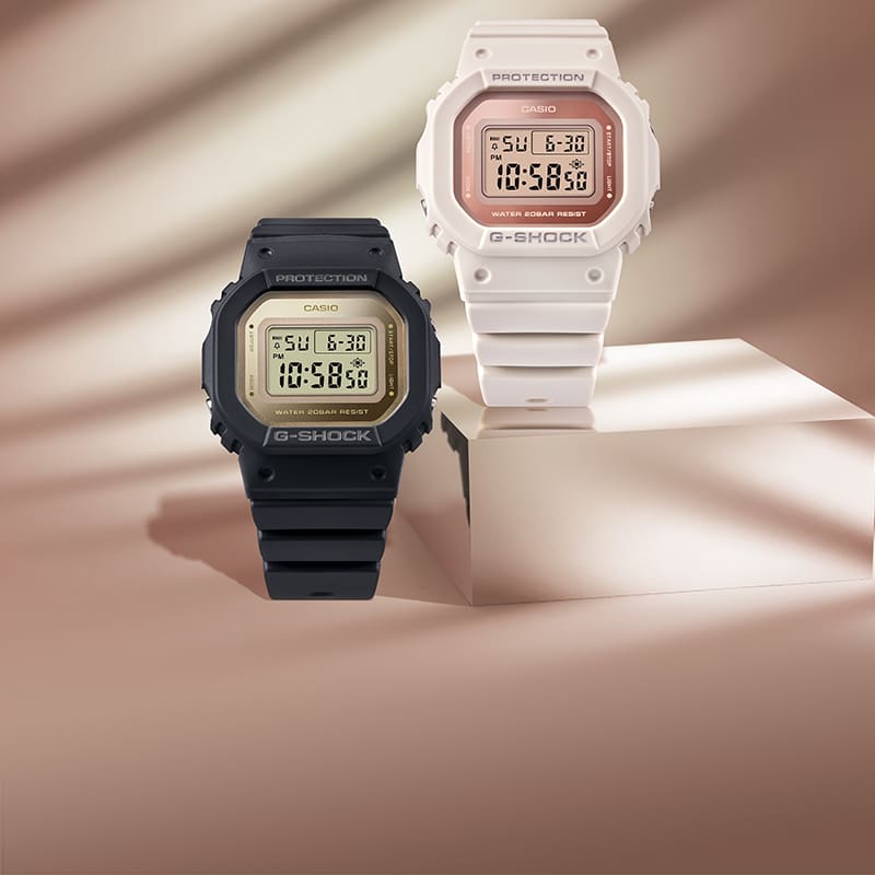 GMDS5600-8 and GMDS5600-1C digital watches on a shimmering pink silk background
