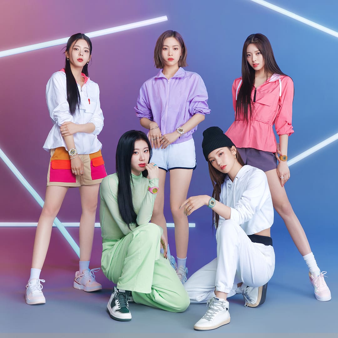 ITZY Band Members posing in front of a blue and purple back drop